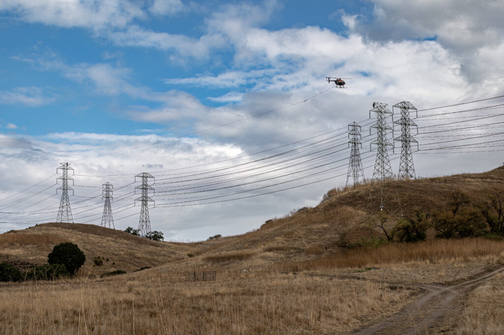 An MD530F helicopter pulls wire